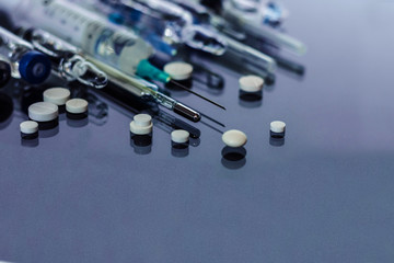 Thermometer, pills, injection vaccine ampoules, syringe for vaccination on glass background,...