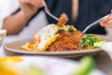 Vietnamese girl eating Com tam - a Vietnamese broken rice with pickles steak grilled pork ribs cucumber onion oil sweet chilies garlic fish sauce fried egg omelet Asian cuisine