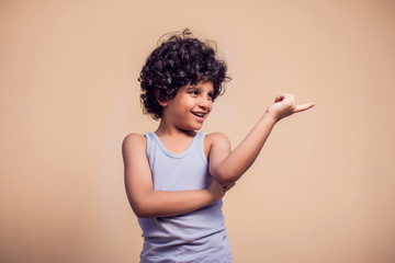 A portrait of smiling kid boy pointing to the side with finger. Children and emotions concept