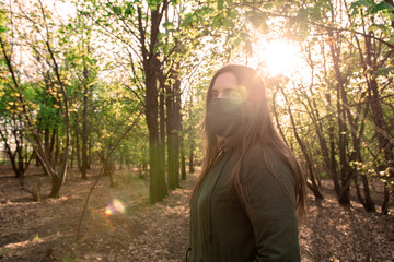 young girl in a medical mask in the park. quarantine. restriction on movement. glare. protection against infections and bacteria.