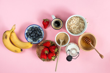 cereal and various delicious ingredients for breakfast on a pink background, top view