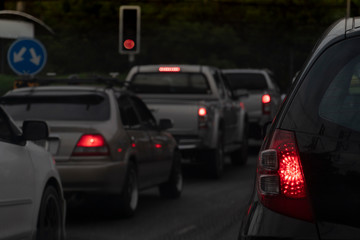 Backside of black car on the road with open brake light. Queue at the red traffic signal at the intersection. on eveing time.