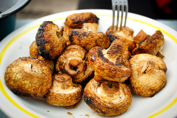 Delicious baked mushrooms lie on a plate next to a fork