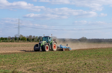 Obraz premium Traktor beim umpflügen des Feldes Hintergrund Himmel mit Wolken im Sommer