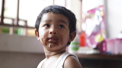 Little boy eating ice cream at home kid has dirty mouth with chocolate summer time concept. 