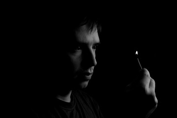 man holds a burning match. Fire from matches on a dark background. Photo with copy space.