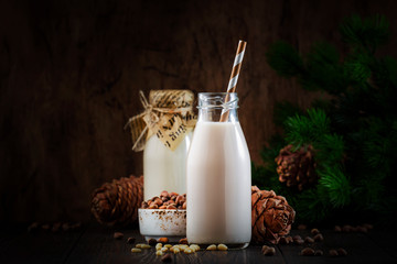 Vegan Cedar nut milk in bottles, closeup, wooden table background. Non dairy alternative milk....