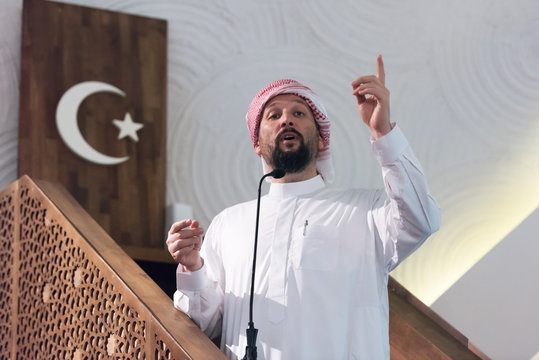 Muslims young arabic Imam has a speech on friday afternoon prayer in mosque. Muslims have gathered for the friday afternoon prayer in mosque and are listening to the speech of imam