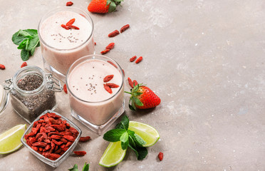 Healthy blended drink. Organic vegan non dairy smoothie with strawberry and goji berries, chia seeds and lime. Gray background with copy space. Top view