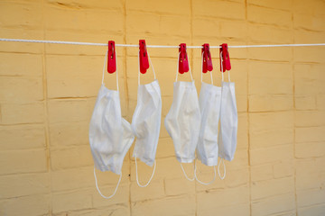 Several white washed used medical masks hung for drying on yellow brick wall background. Drying...