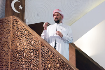 Muslims young arabic Imam has a speech on friday afternoon prayer in mosque. Muslims have gathered...