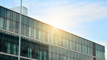 Glass building with blue sky background. Modern office building detail, glass surface clouds reflected in windows of modern office building.