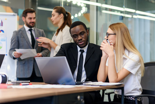 Professional male and female international business people in meeting room discussing joint project and reviewing business documents. Business teamwork concept.