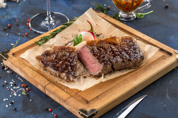 Grilled Ribeye Steak with knife on wooden board on blue background
