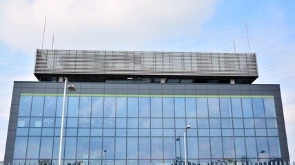 Glass building with blue sky background. Modern office building detail, glass surface clouds reflected in windows of modern office building.