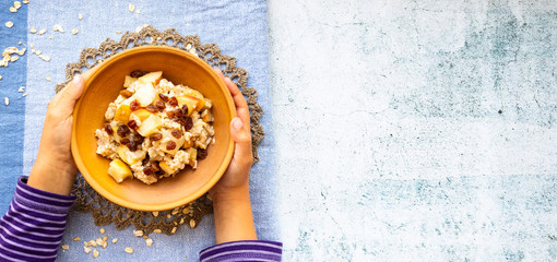Oatmeal granola fruit porridge with banana, apples and raisins. Healthy sweet vegan breakfast. Copy space