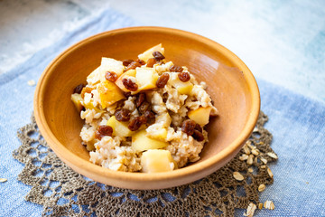Oatmeal granola fruit porridge with banana, apples and raisins. Healthy sweet vegan breakfast. 