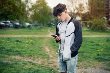 A teenage boy holds a modern phone in his hands and starts to call his parents to say that everything is fine with him, because he went to a friend in another city
