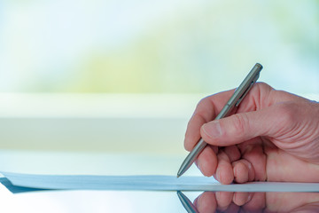 Man signs a document form with a ballpoint pen in the office