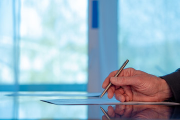 Man signs a document form with a ballpoint pen in the office