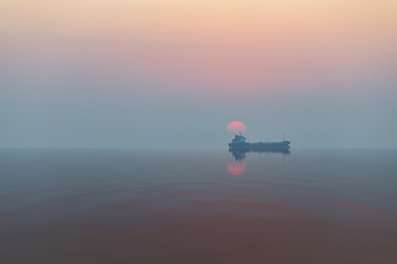 Fototapeta na wymiar Landscape view in sunset general cargo ship with reflection
