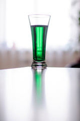 a glass of green liquid stands in front of the window