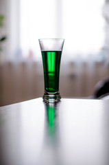 a glass of green liquid stands in front of the window
