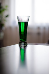 a glass of green liquid stands in front of the window