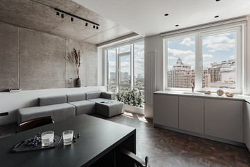 bright kitchen with dark table, convenient location of kitchen accessories and equipment, modern style, White walls, marble working surface and parquet floor. There s a glass of milk on the table and