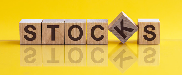 STOCKS - word from wooden blocks with letters, sorry concept, yellow background.