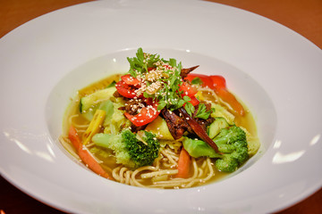 delicious asian noodle soup with vegetables on white plate