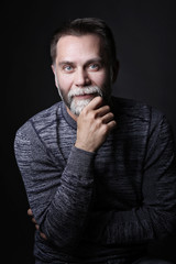 Portrait of a middle-aged man, he stands and looks at the camera, holding by the hand a beard on a...