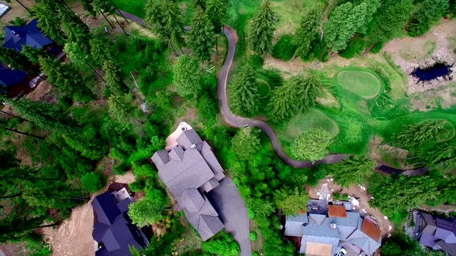 Aerial Cascade Mountains with golf course, community with houses and roof tops with roads and pine trees. Cle Elum, WA