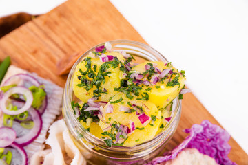 Russian traditional snack on a wooden board on a white background. Jar of boiled potatoes in the center of the photo