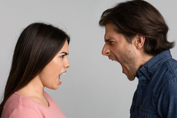 Relationship Crisis. Angry Couple Screaming At Each Other Over Light Background