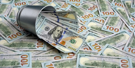 A bucket of dollars оn a background of  pile of hundred-dollar bills. The concept of wealth and...