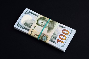 A pack of 100 us dollar bills wrapped in a 1 yuan Chinese bill on black background. The concept of  conflict of interest between China and the United STATES