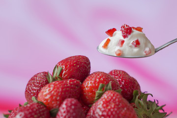 Strawberry yogurt in a spoon, against the background of fresh strawberries