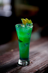 Cocktail with ice berries mint on bar counter daylight side view bokeh