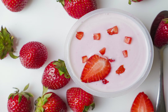 Bowl of delicious yogurt and strawberries rotates on the table. The view from the top