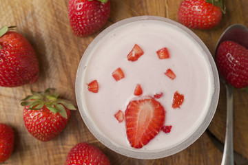 Bowl of delicious yogurt and strawberries rotates on the table. The view from the top