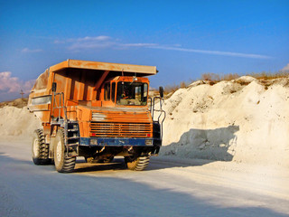Dump track carrying the industrial cargo and moving on the road inside the chalk quarry