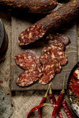 Beef jarky sausage with spices on wooden board with garlic pepper jar wooden texture top