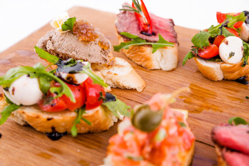 Assorted bruschett on a wooden board on a white background