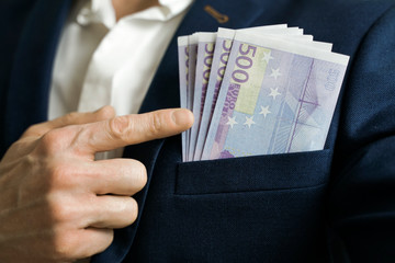 Money success concept. 500 euro bills in businessman jacket pocket. Symbol of success and wealth.