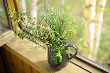 spring branches in a black vase on open window. fresh and minimal style concept. clean and uncluttered room. scandinavian design. wooden old house window with green plants in a vase.