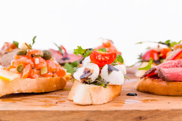 Assorted bruschett on a wooden board on a white background