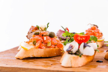 Assorted bruschett on a wooden board on a white background