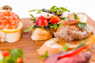 Assorted bruschett on a wooden board on a white background
