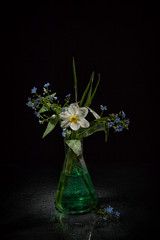 Bouquet of white and blue flowers in drops of water on a black background